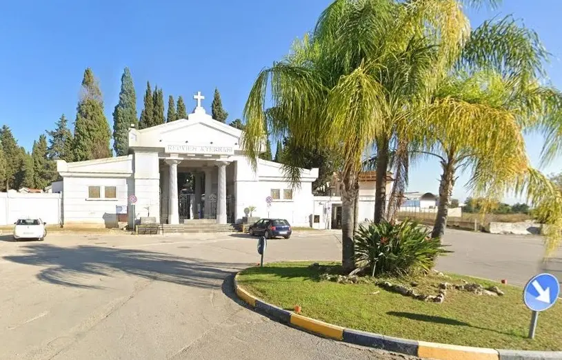 Facciata d’ingresso del Cimitero Comunale di Battipaglia, con colonne bianche in stile classico, scritta “Requiem Aeternam” e palma decorativa in primo piano.